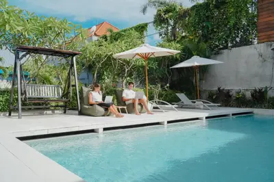 two people sitting on chairs next to a swimming pool at Bali Bustle Kuta Coliving & Coworking Space in Legian