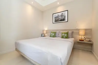 a bedroom with a large white bed with two green pillows at Bali Bustle Kuta Coliving & Coworking Space in Legian