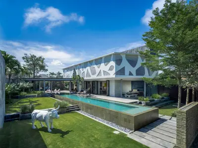 a house with a pool and a cow statue in the yard at Villa Issi in Seminyak