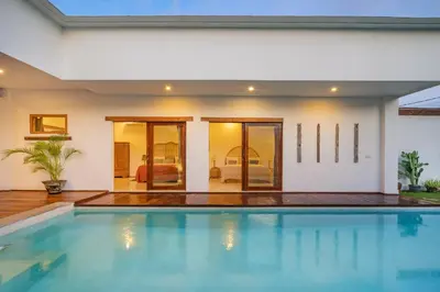 a swimming pool in front of a house at Villa Nuga By DreamAwayBali in Seminyak