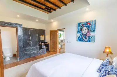 a bedroom with a king sized bed and a bathroom at Villa Nuga By DreamAwayBali in Seminyak