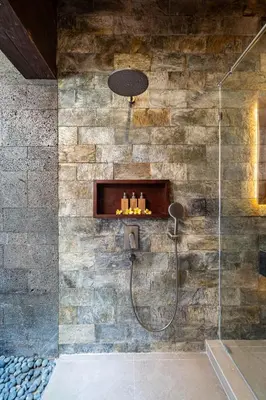 a bathroom with a shower with a stone wall at Villa Bolon in Kuta