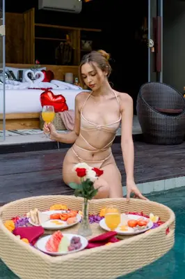 a woman in a swimsuit sitting in a pool with a tray of food at Villa Dijabu in Kuta