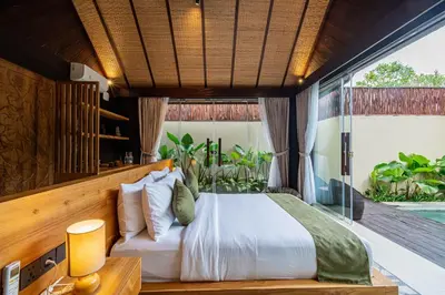 a bedroom with a bed and a large window at Villa Dijabu in Kuta