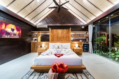 a bedroom with a large bed in a room with windows at Villa Dijabu in Kuta