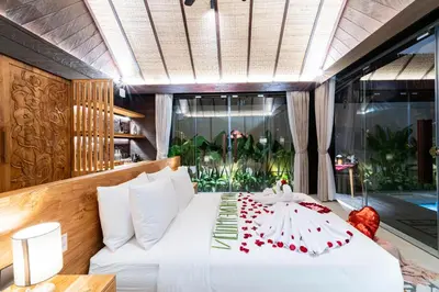 a bedroom with a white bed with red candies on it at Villa Dijabu in Kuta