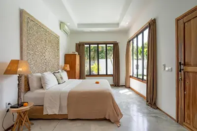 a bedroom with a bed and a couch and windows at Villa N'Zo By DreamAwayBali in Seminyak