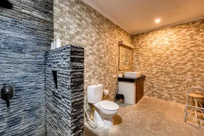 a bathroom with a toilet and a brick wall at Dion Villas Berawa only 5 Minutes by scooter to Finns beach club in Canggu