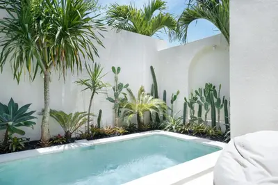 a swimming pool in a garden with palm trees at Villa Benteke Umalas in Kerobokan