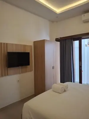a bedroom with a bed with a tv on the wall at Ayoolasudi in Kerobokan