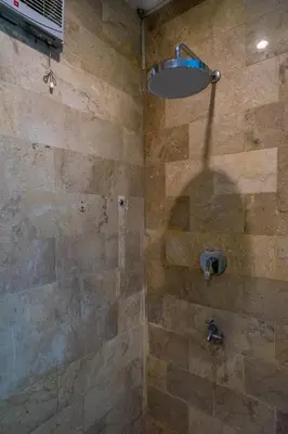 a bathroom with a shower with a stone wall at 2BR Villa walking distance to Finns & Atlas in Canggu