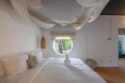 a bedroom with a large white bed with a round window at 2BR Villa in Umalas next to Seminyak & Canggu in Kerobokan