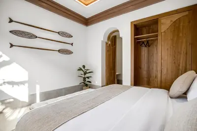 a bedroom with a white bed and a wooden door at Villa Advaya by Maheswara in Seminyak