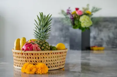 a basket of fruit on a table with a vase of flowers at Villa Wampu By DreamAwayBali in Seminyak