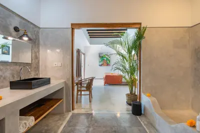a kitchen and living room with a table and a plant at Villa Wampu By DreamAwayBali in Seminyak