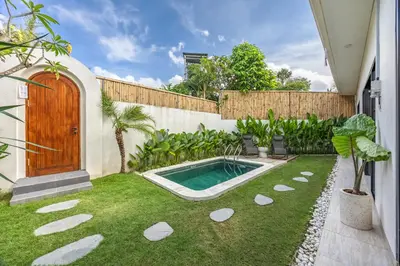 a backyard with a swimming pool and a wooden door at Pool Garden Private 2BR Villa - 10 min to Finns Beach Club in Canggu
