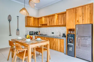 a kitchen with wooden cabinets and a wooden table and chairs at Villa D Canggu in Canggu