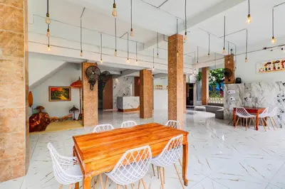 a dining room with a wooden table and white chairs at Townhouse Oak Legian Near Kuta Beach Formerly Sayang Maha Merta in Legian