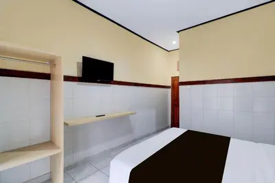 a bedroom with a bed and a tv on the wall at Townhouse Oak Legian Near Kuta Beach Formerly Sayang Maha Merta in Legian