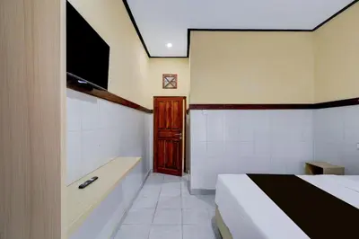 a bedroom with a bed and a tv and a tub at Townhouse Oak Legian Near Kuta Beach Formerly Sayang Maha Merta in Legian