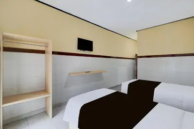 a bedroom with two beds and a tv on the wall at Townhouse Oak Legian Near Kuta Beach Formerly Sayang Maha Merta in Legian