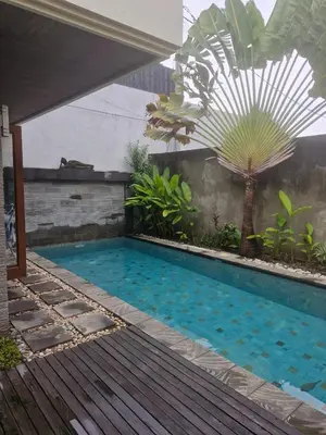 a pool in a backyard with a palm tree at Max Guest House in Seminyak
