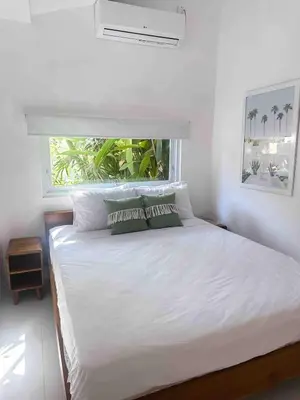 a bedroom with a white bed with a window at The Pink Door Villa in Legian