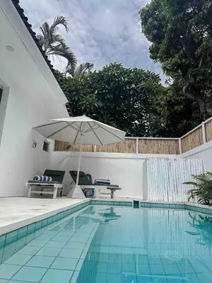 a swimming pool with a table and an umbrella at The Pink Door Villa in Legian