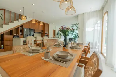 a dining room with a long wooden table with chairs at Villa Agua Dream Canggu hideaway in Canggu