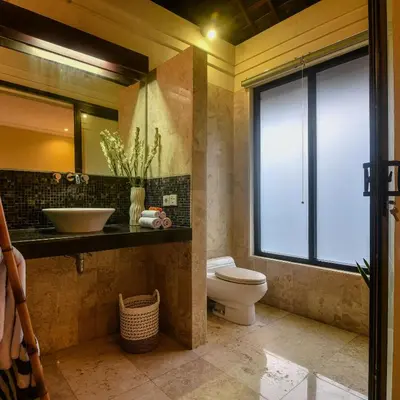 a bathroom with a toilet and a sink and a window at Villa EL Noya Umallas in Badung