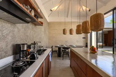 a kitchen with a counter and a table with chairs at Solencia Villa by Betterplace in Jimbaran