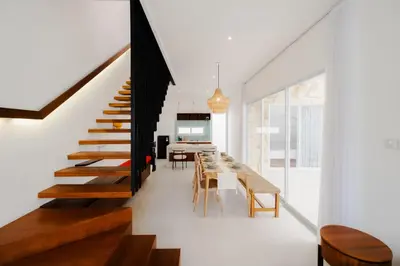 a dining room and kitchen with a long table and stairs at Casa De Vero Amore in Jimbaran