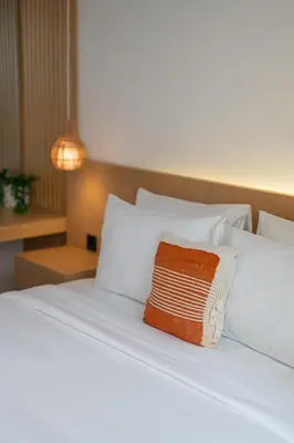 a white bed with a brown and white pillow on it at Casa De Vero Amore in Jimbaran