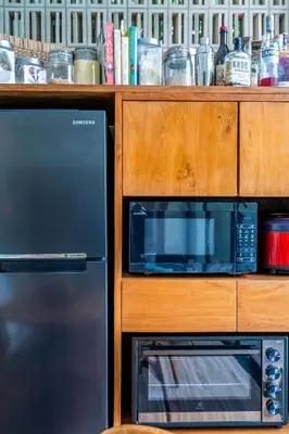 a kitchen with a microwave and a wooden cabinet at Tropical 2BR Villa with Private Pool in Canggu in Canggu