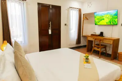 a hotel room with a bed and a desk and a television at Purnava Village by Behomy in Ngurah Rai International Airport