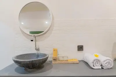 a bathroom with a sink and a mirror at Purnava Village by Behomy in Ngurah Rai International Airport