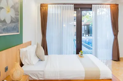 a bedroom with a white bed and a window at Purnava Village by Behomy in Ngurah Rai International Airport