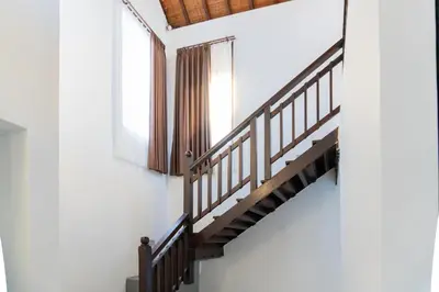 a wooden staircase in a building with a window at Purnava Village by Behomy in Ngurah Rai International Airport