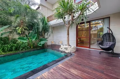 a house with a swimming pool and a chair on a wooden deck at Elf Belly 4 BR Canggu Heart Vila CYN in Canggu