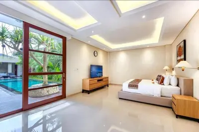 a bedroom with a bed and a tv and a pool at Elf Belly 4 BR Canggu Heart Vila CYN in Canggu