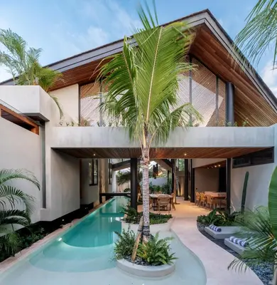 a house with a palm tree in front of it at House of Winds Complex - Lush 9BR Exotic Escape - 3x3BR Villas near Canggu in Kerobokan