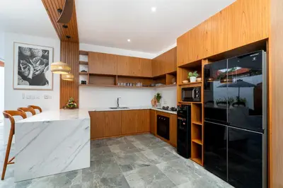 a kitchen with wooden cabinets and a black refrigerator at Villa Sunset Waters in Legian
