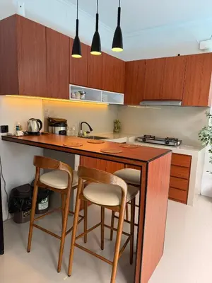 a kitchen with wooden cabinets and a counter with bar stools at Erindra Villa in Pesanggaran