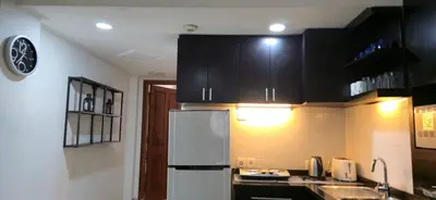 a kitchen with black cabinets and a white refrigerator at The Palmana Tropical Roofline Jayakarta Residence 40 in Badung