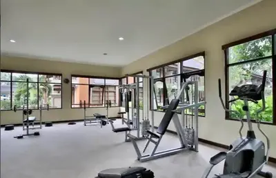 a gym with cardio equipment in a large room with windows at The Palmana Tropical Roofline Jayakarta Residence 40 in Badung