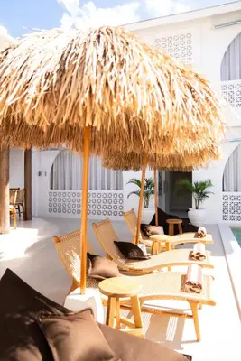 a patio with chairs and a straw umbrella at Antana Hotel in Canggu