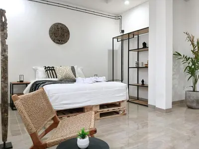 a bedroom with a bed and two chairs at Nice Place To Stay - Cozy Living in Seminyak
