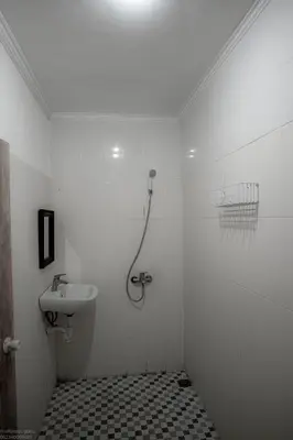 a white bathroom with a shower and a sink at Mirri House Kerobokan in Seminyak
