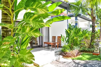 a garden with a bench and palm trees at Palm Garden Bali in Nusa Dua