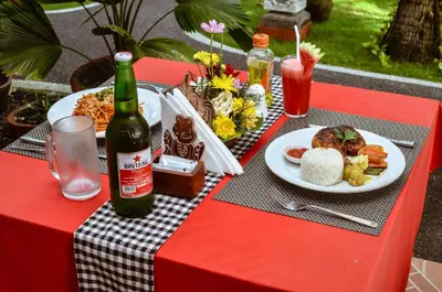 a red table with a plate of food and a bottle of beer at Palm Garden Bali in Nusa Dua